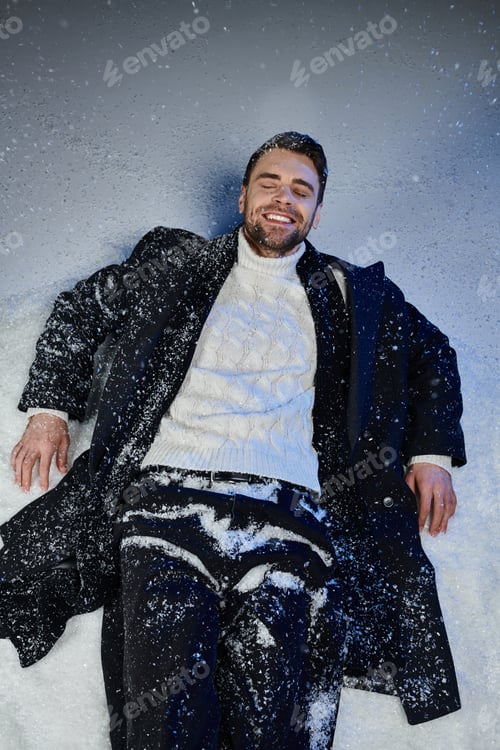 Preview: A charming young man enjoying a snowy winter day while wearing a stylish black coat and sweater