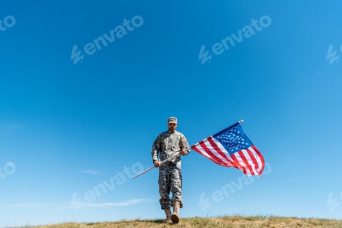 Preview: handsome soldier in uniform walking with american flag