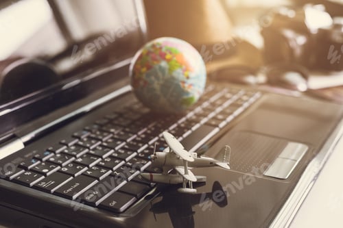 Preview: Toy airplane on laptop keyboard with globe and camera