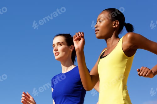 Preview: Two young women jogging against blue sky