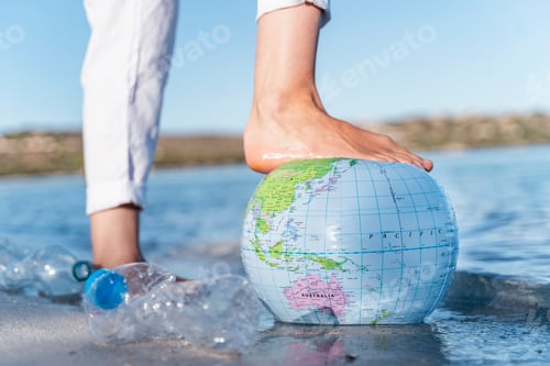 Preview: Man's foot on Earth beach ball, close-up