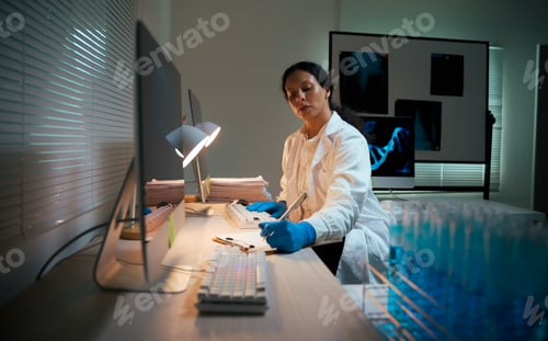 Preview: Female scientist working late researching genetic data