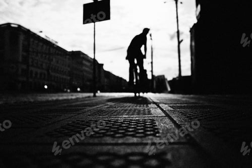 Preview: Low angle greyscale shot of a person riding a bicycle on the street