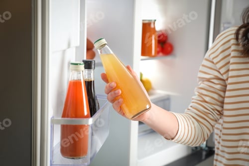 Preview: Young woman taking juice out of refrigerator, closeup