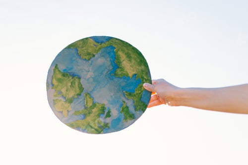 Preview: Woman holding planet in hands against green spring background. Earth day