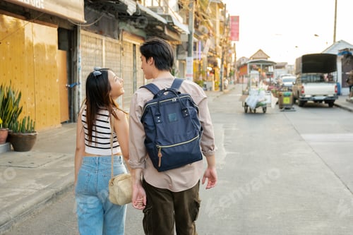 Preview: Young tourists couple walking in bangkok, thailand, holding hands and smiling