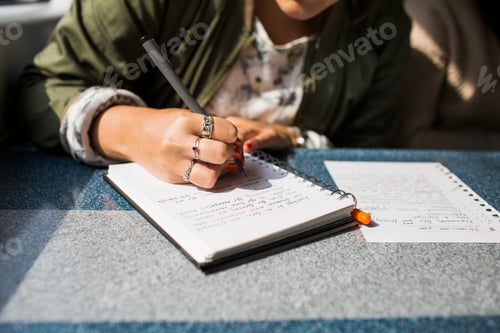 Preview: Midsection of businesswoman writing on diary in train