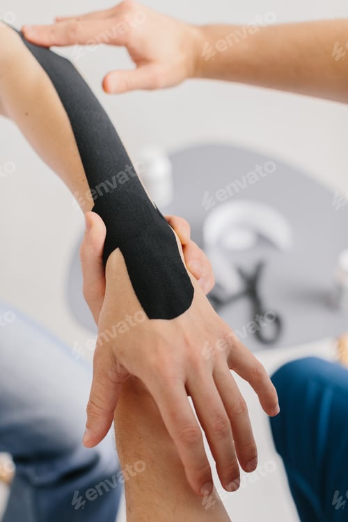 Preview: Close-up of a healthcare professional applying kinesiology tape to a patient's arm.