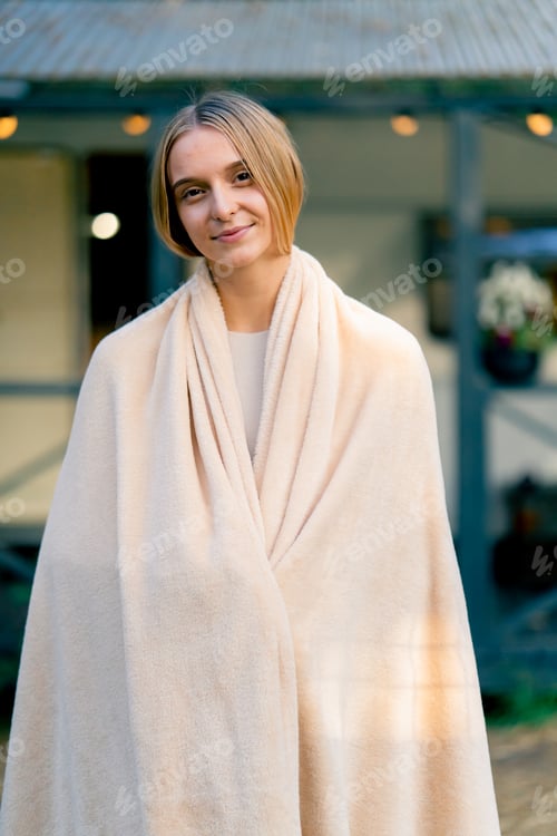 Preview: Portrait of a young beautiful smiling girl with a blanket on her shoulders glamping