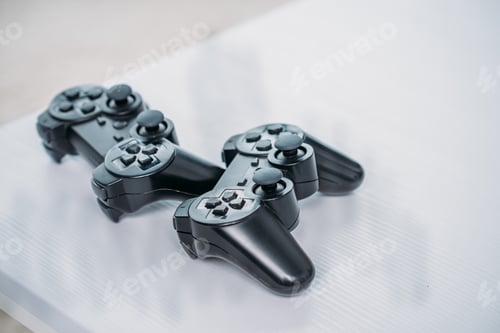 Preview: close up view of black gamepads for playing video game on grey tabletop