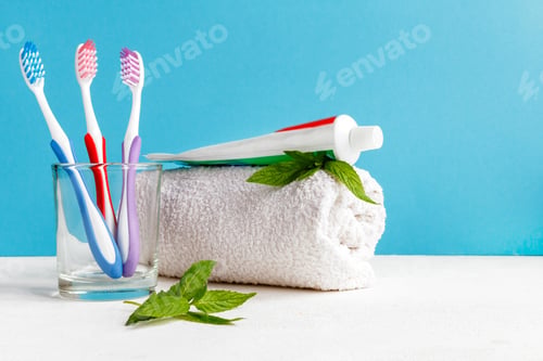 Preview: Healthy teeth. Toothbrush in a glass and toothpaste and mint leaves a bath towel on the table in the
