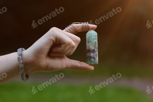 Preview: Woman meditating with crystal to heal or restore her aura outdoors, closeup