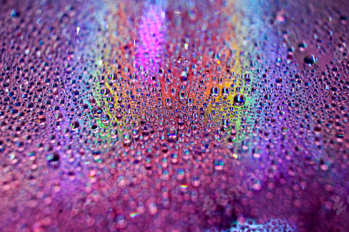 Preview: Selective focus shot of colorful reflective water drops on a digital disc surface