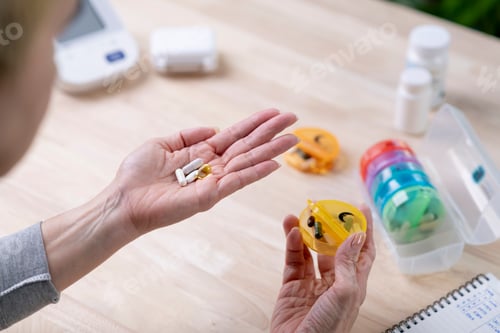 Preview: Woman holds pills, taken from a daily pill box.