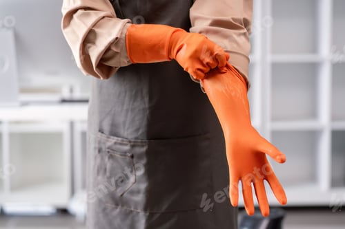 Preview: Professional Maid or Housekeeper Wearing Orange Gloves and Apron Ready for Cleaning Duties in a