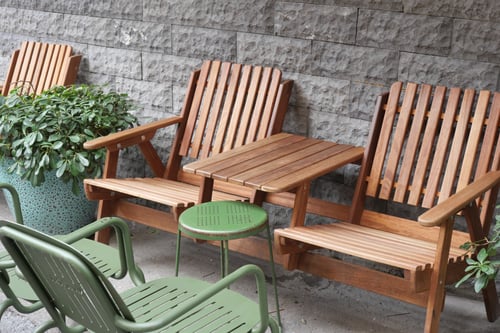 Wooden chairs and small table arranged near a stone wall