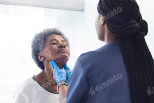 Preview: African american female doctor testing neck of senior female patient in hospital room