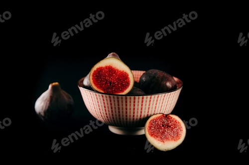 Preview: Bowl filled with fresh figs with some figs on the side on a black background