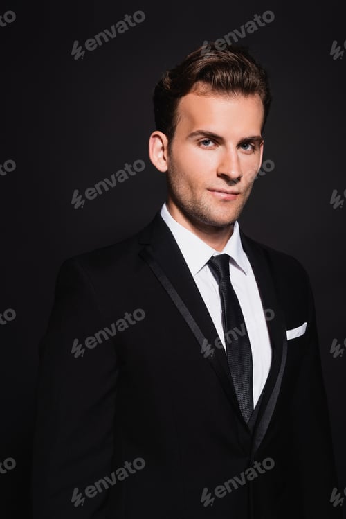 Preview: young confident man in elegant suit looking at camera on black