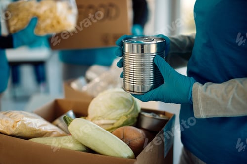 Preview: Close-up of a volunteer packing food in donation box.
