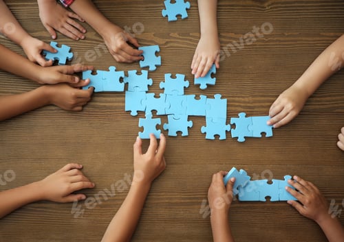 Preview: Top view of little children playing puzzle together at table, focus on hands. Unity concept