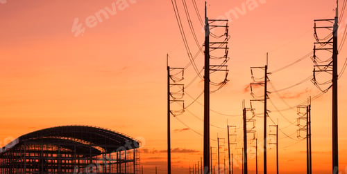Preview: Silhouette of industrial building structure with row of electric poles against sunset sky background
