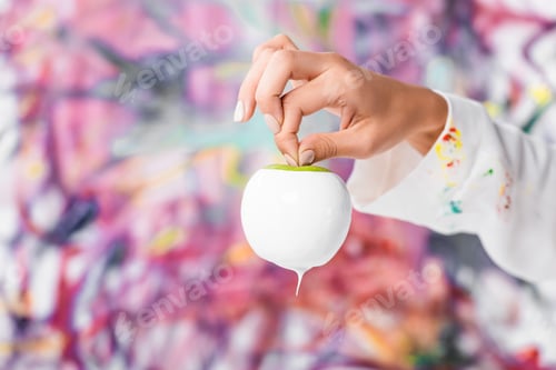 Preview: close up of female hand holding white painted apple