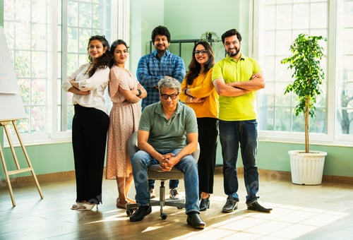 Preview: Confident Indian Asian business team in casuals, smiling, celebrating success in modern workspace