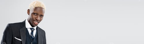 Preview: smiling and young african american man in suit isolated on grey, banner