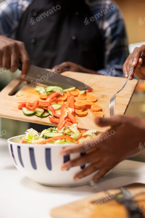 Preview: Close up of person adding freshly cut veggies in a bowl to make delicious salad