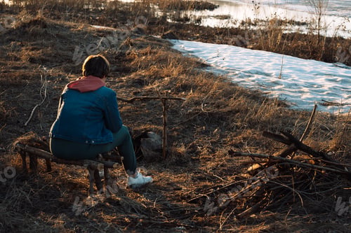 Preview: Girl sits on makeshift bench in front of fire pit