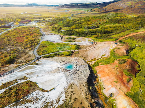 Preview: Drone view of geyser Strokkur in Iceland, with crowds of tourists walking past it