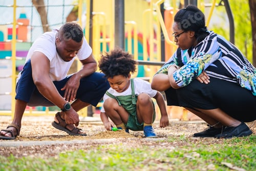 Preview: Happy African American father with son play guitar in the playground area together in the park