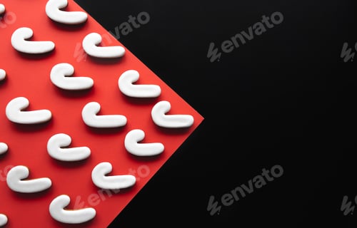 Preview: A lot of gingerbread candy cane shaped cookies on a red background.