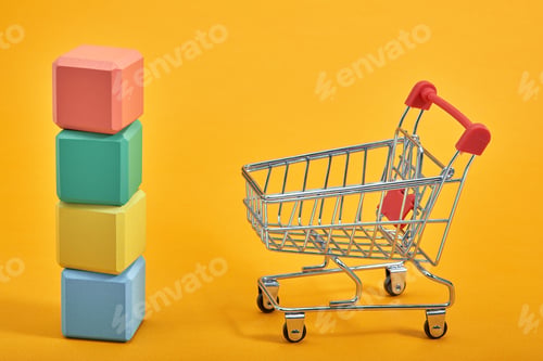 Preview: empty wooden cubes mockup style, copy space with shopping trolleys on yellow background. Colourful