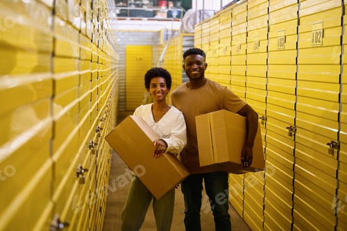 Preview: Curly-haired guy and girlfriend are standing in warehouse with cardboard boxes