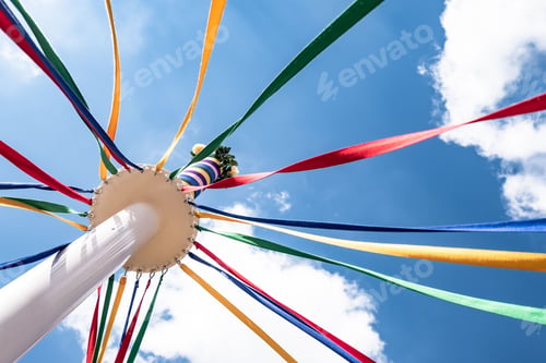 Preview: Low angle shot of the colorful bands of maypole on blue cloudy sky background