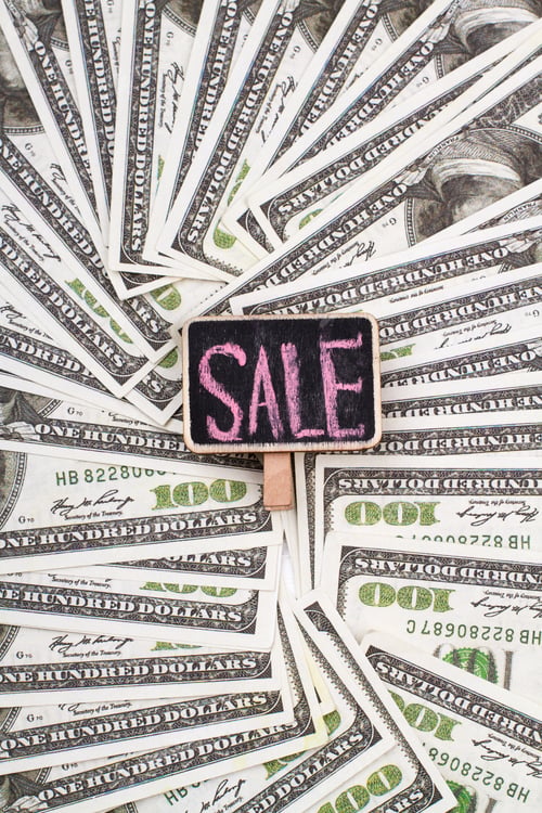 Preview: Chalkboard with sale word on a pile of dollars.