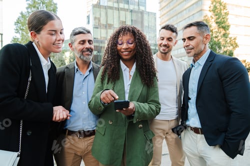 Preview: Group of diverse coworkers engaged in discussion while looking at a smartphone outdoors. Teamwork of