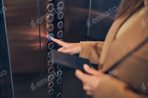 Preview: Female staying in lift and holding her mobile