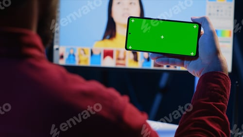 Preview: Photo editor uses green screen mobile phone to watch tutorial, learning to color correct photographs