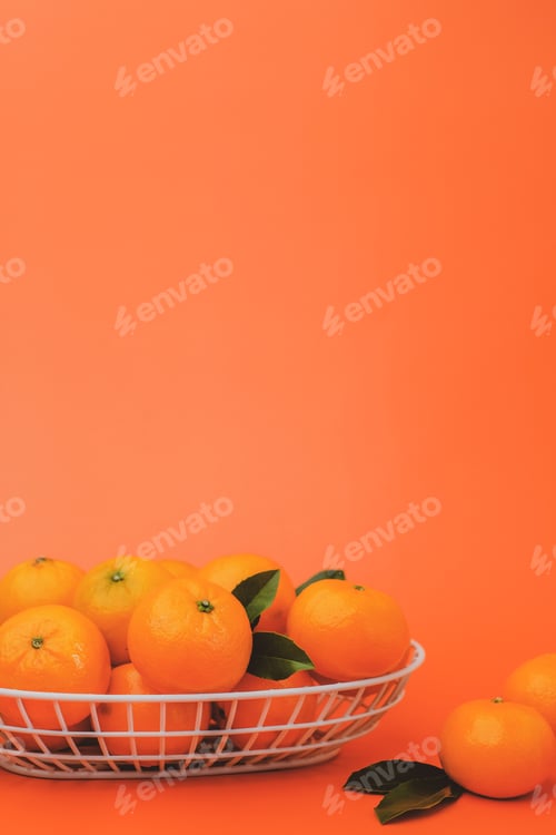 Preview: the vertical view of orange in the basket on bright orange background. with copy space