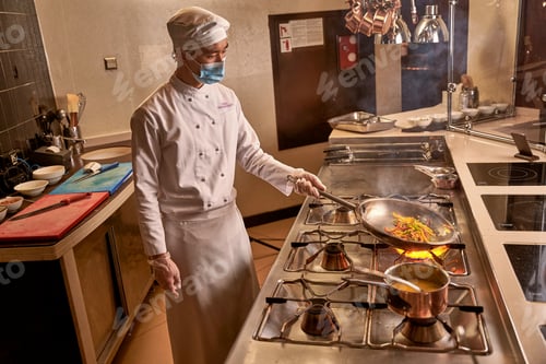 Preview: Asian kitchen worker frying vegetables on big flame