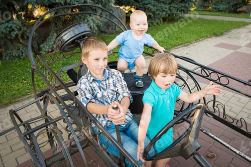Preview: Three happy children playing on a toy car outdoors. Kids having fun in spring park
