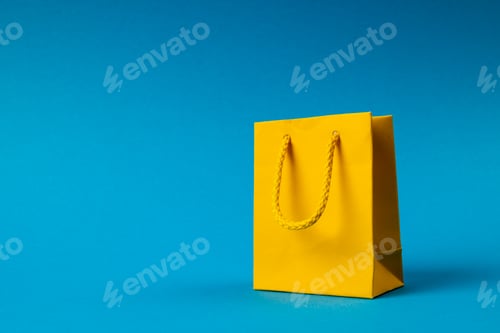 Preview: Composition of yellow paper shopping bag on blue background