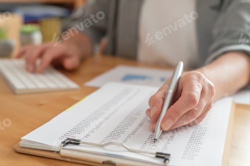Preview: Person using a pen to review financial numbers