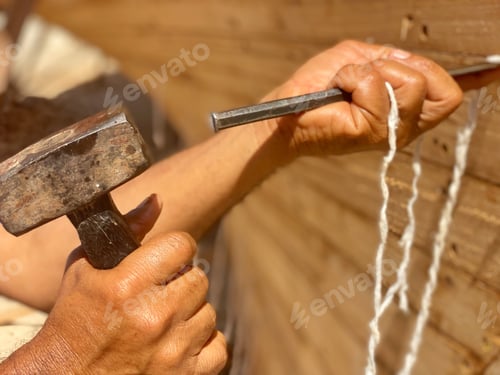 Preview: Carpenter helps seal the gaps in a traditionally built wooden dhow fishing boat with hammer and awl