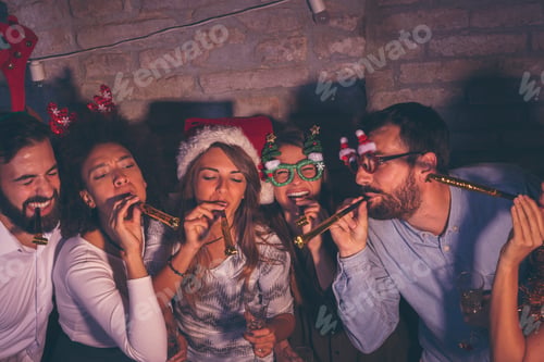Preview: Friends blowing party whistles at New Year's party midnight countdown