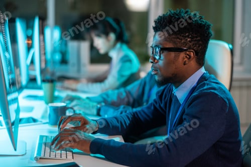 Preview: Young serious businessman in eyeglasses and formalwear looking at screen of computer
