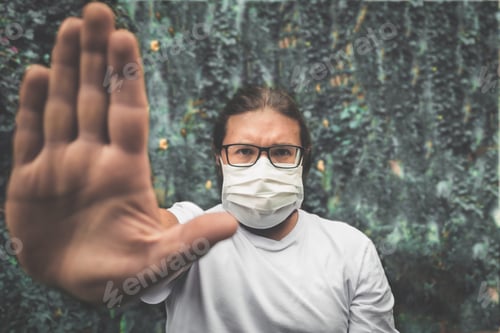 Preview: Person wearing a protecting face mask showing a stop gesture to stop coronavirus outbreak